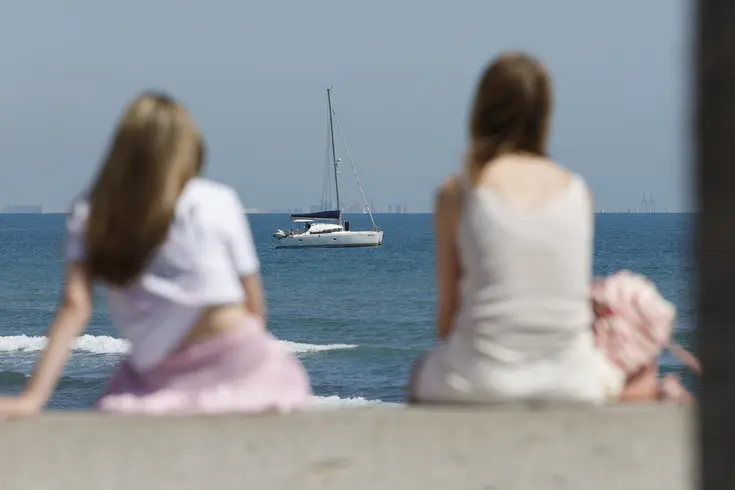 Dos personas sentadas frente al mar en un día soleado en València